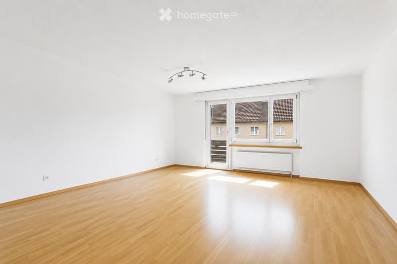Empty room with light wooden flooring, white walls, and large windows with blinds. No furniture or equipment is present.