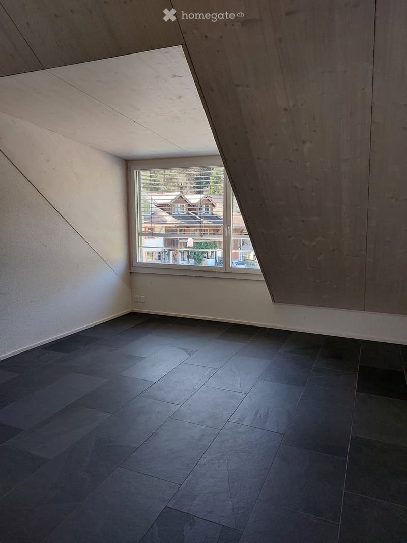 Empty room with grey tiled floor, white walls, and large window offering view of neighboring houses.