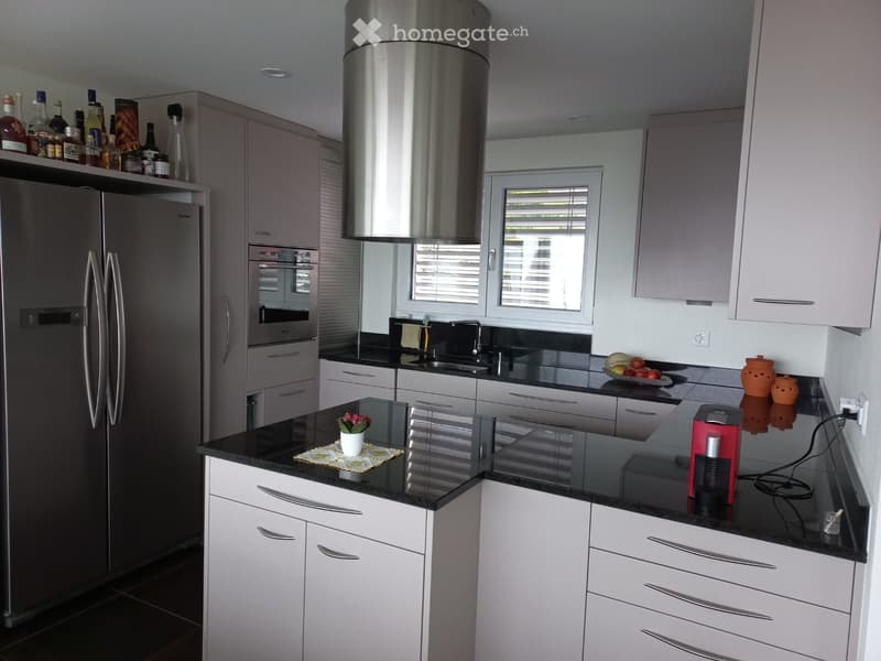 Modern kitchen with white cabinets, black countertops, stainless steel appliances, and various decorative items on the counters.