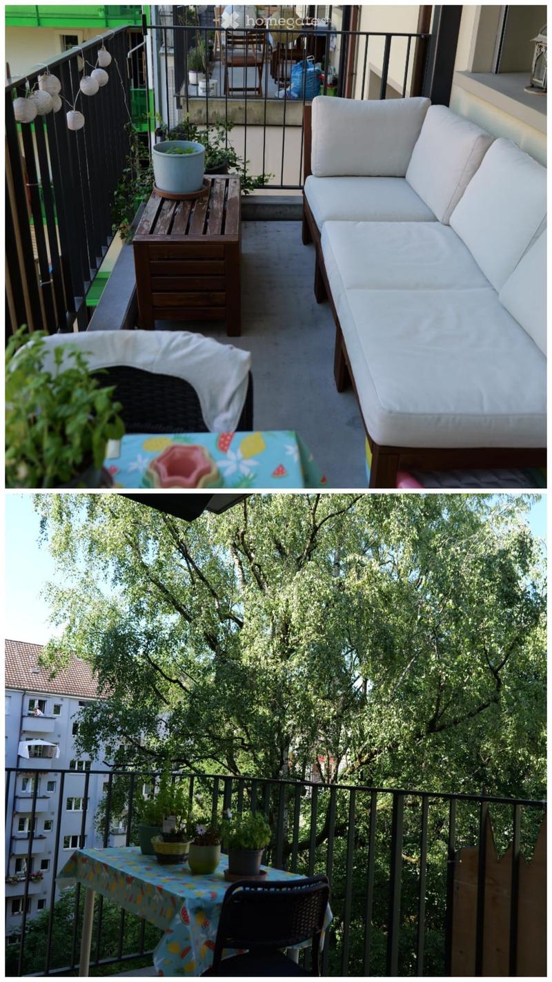 Balcony with a white sofa, small wooden table, colorful tablecloth, potted plants, and hanging lanterns.