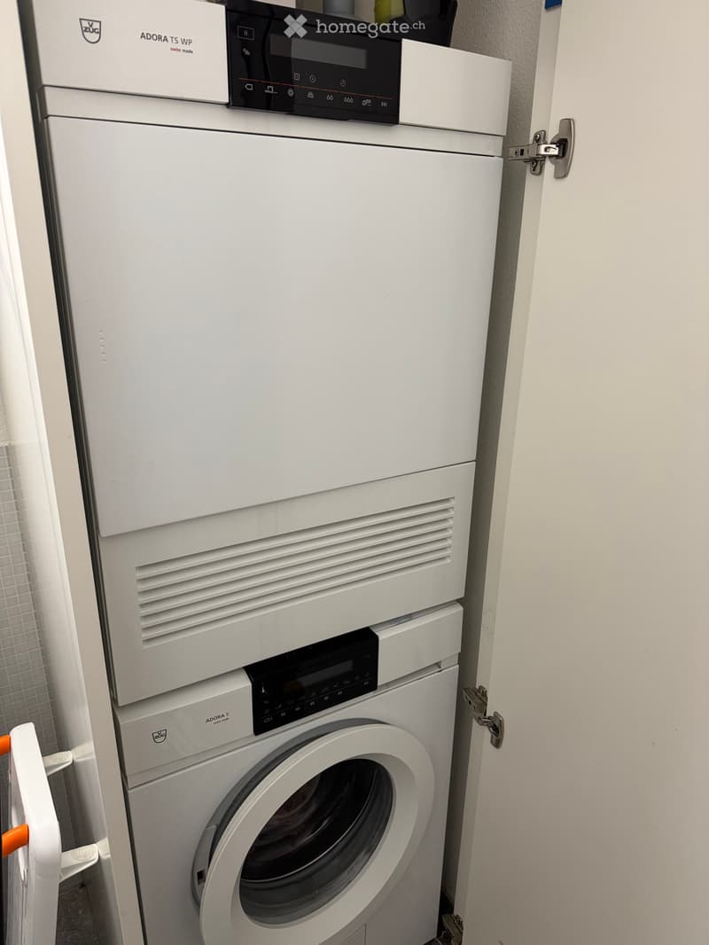 A compact bathroom with a white washing machine and a white dishwasher stacked vertically, featuring modern control panels.