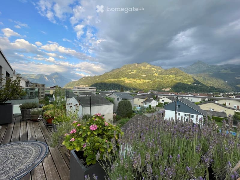 Balcony with wooden decking, lavender plants, potted flowers, and a scenic mountain view.