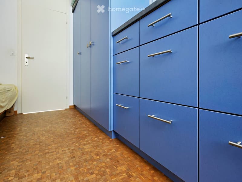 Empty room with light blue cabinets and a wooden floor. No furniture or equipment visible.