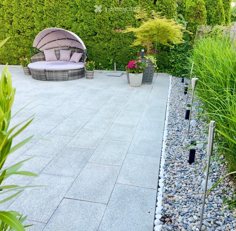 Garden area with a round daybed, potted plants, and decorative lighting.
