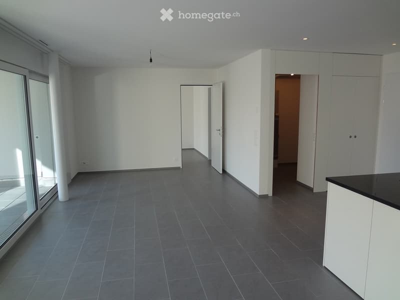Empty room with grey tiled floor, white walls, large glass door, and white cabinetry.