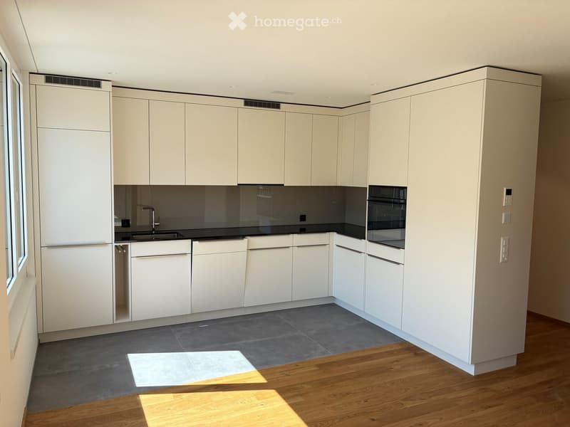 Modern kitchen with white cabinets, black countertops, and stainless steel appliances. Features a sink, faucet, and oven.