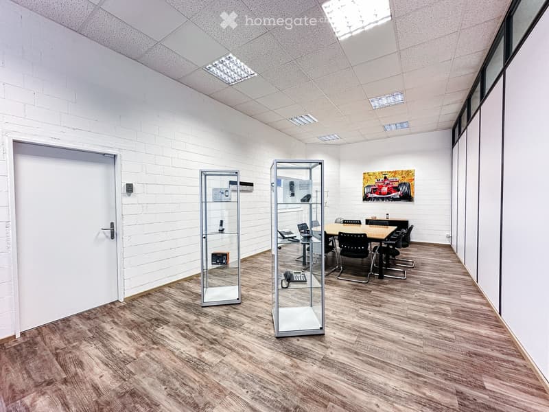 empty room, wooden floor, meeting table, display cases, white walls, ceiling lamps