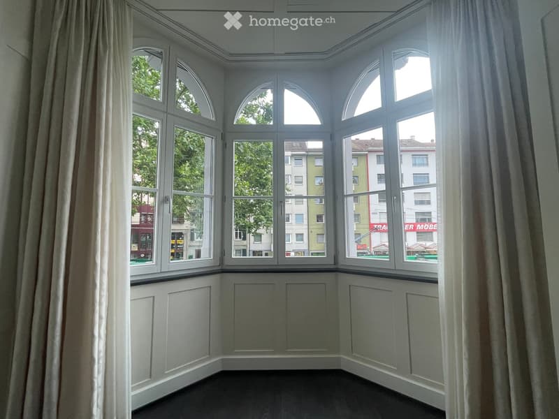 Empty room with large bay windows, white walls, and dark flooring. No furniture or equipment present.