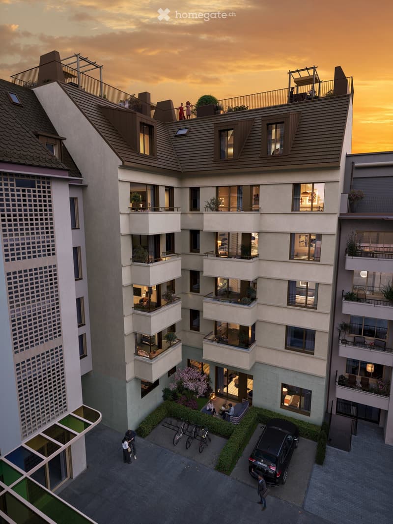 A modern apartment building with several balconies and a parking area with a black SUV and bicycles.