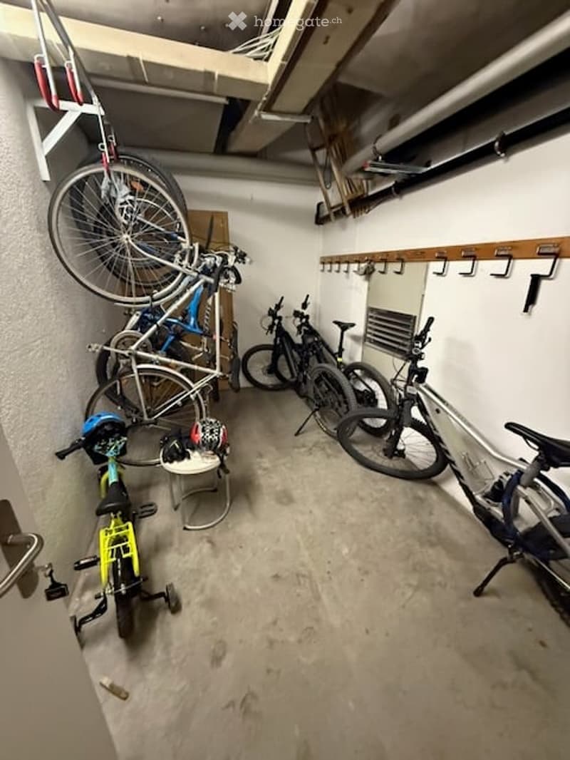 Garage with multiple bicycles stored on racks and a small stool on the floor.