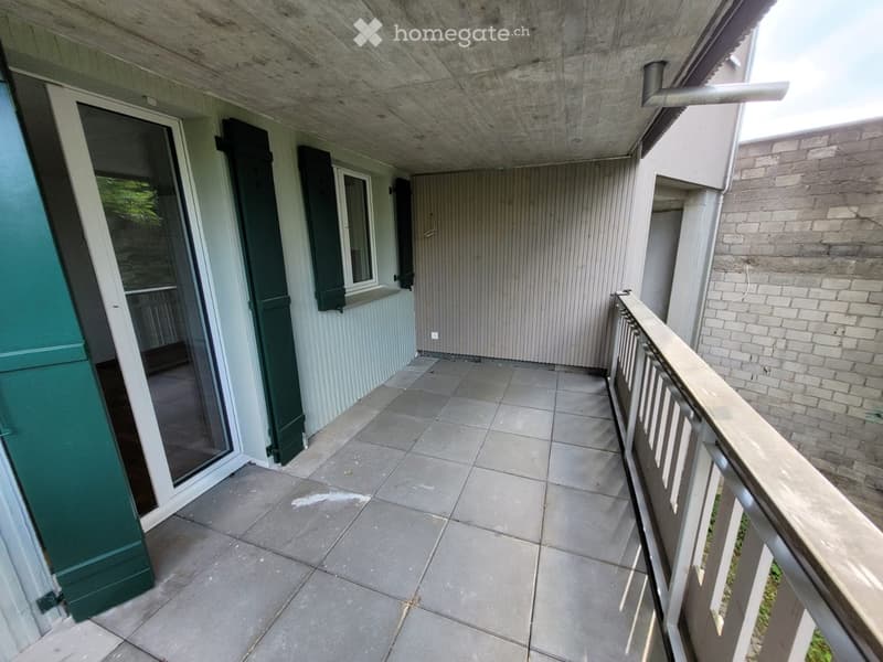Balcony with tiled floor, wooden railing, and sliding glass door leading to interior space.