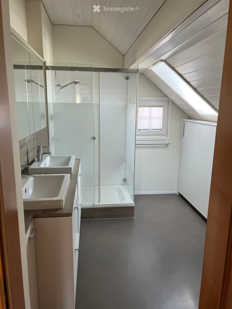 Attic bathroom with two sinks, large shower, and a window with blinds