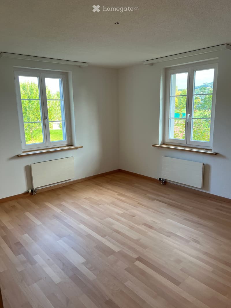 empty room, hardwood floor, two large windows, white walls, radiators, wooden window sills