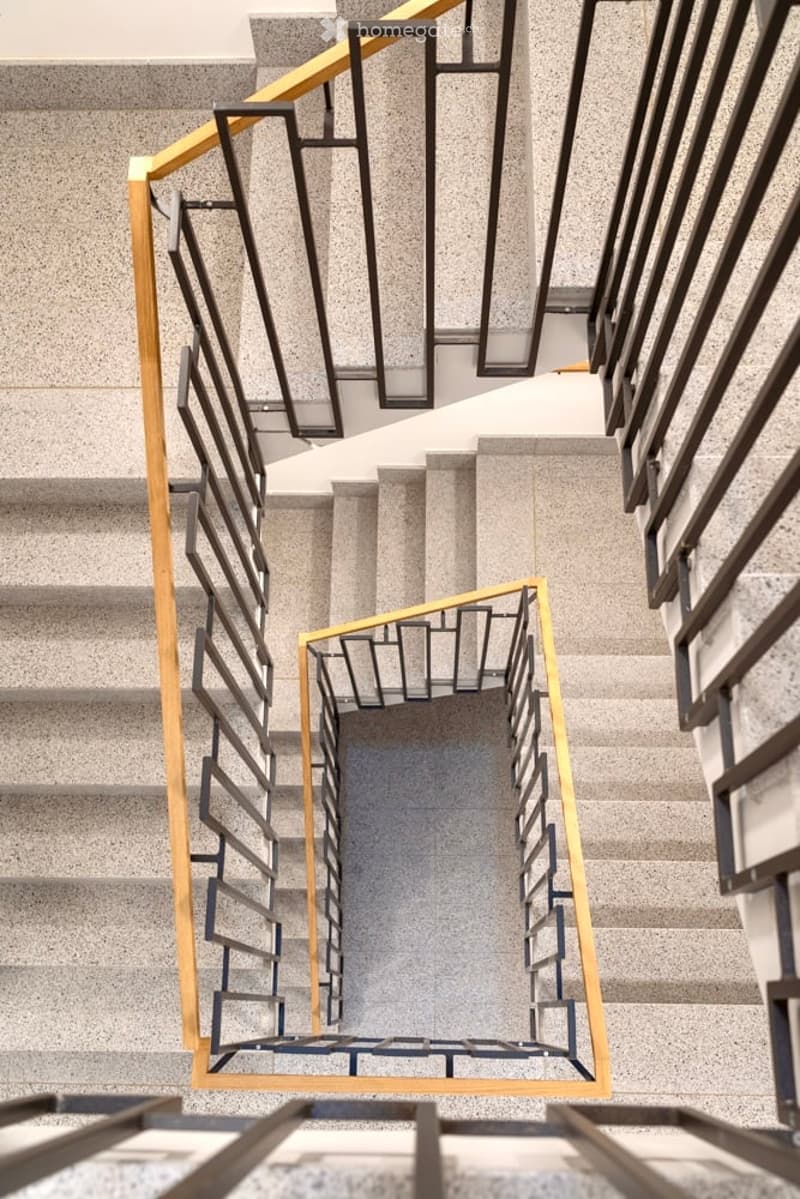 Modern staircase with sleek, geometric black and gold railings, concrete steps, and clean lines.