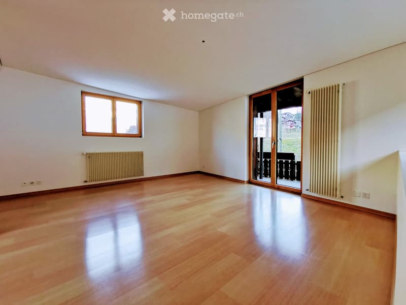 Empty room with wooden flooring, white walls, two radiators, a large window, and a sliding glass door leading to a balcony.