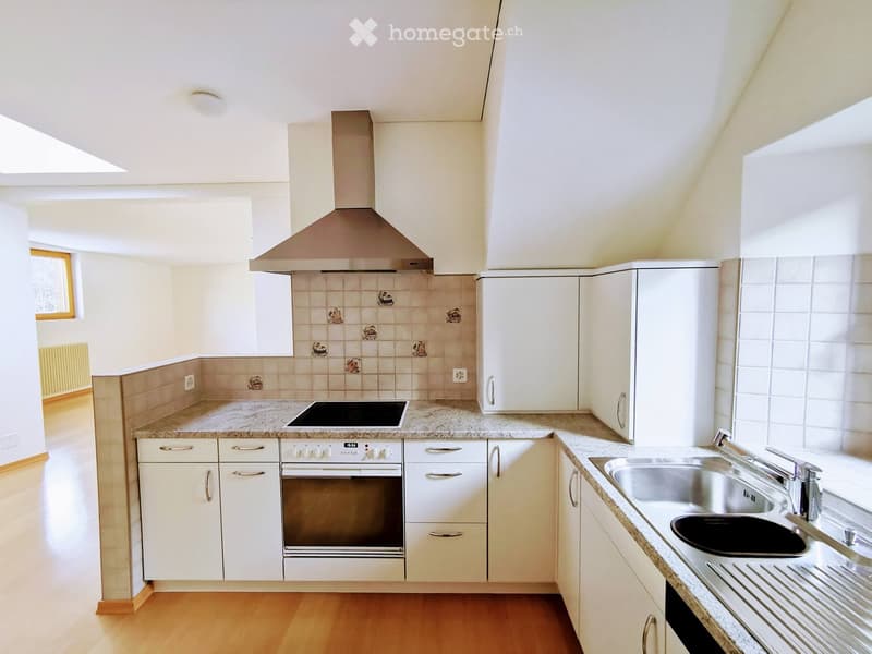 Modern kitchen with white cabinets, granite countertops, stainless steel sink, oven, and range hood. Light-colored tiles on backsplash and wooden flooring.