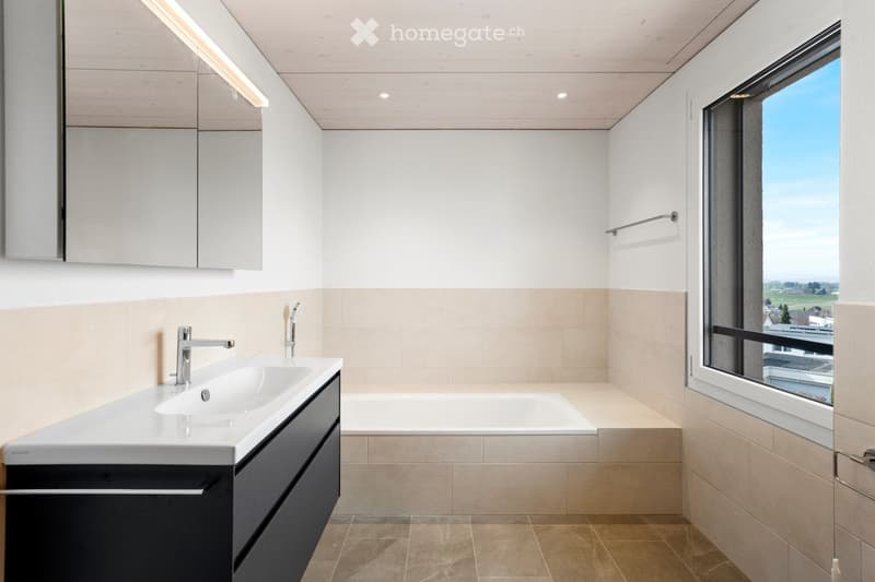Modern bathroom with a white sink, sleek faucet, bathtub, and large window offering a scenic view.