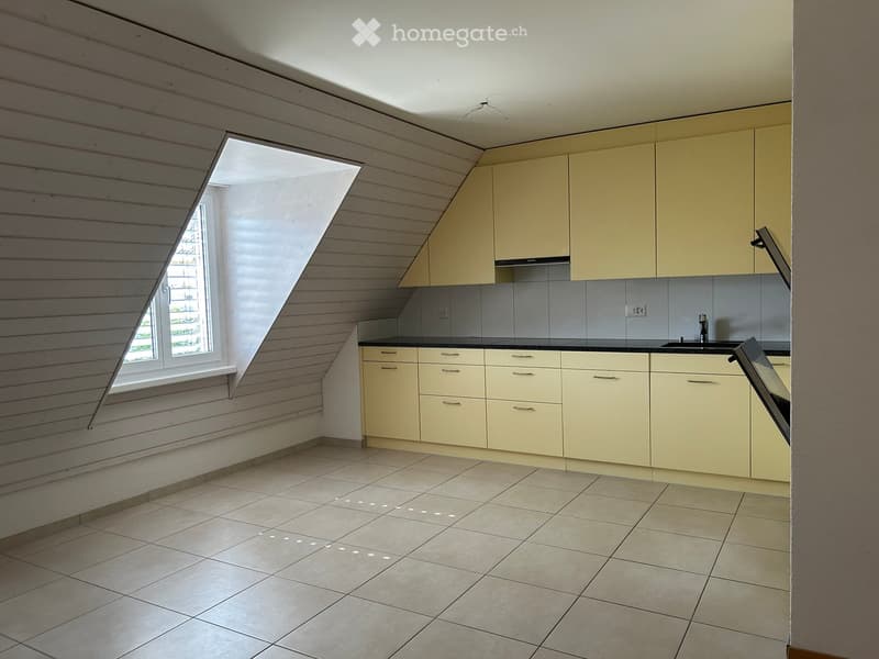 Bright kitchen with light yellow cabinets, tiled floor, and a large window offering natural light.