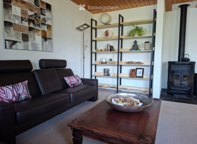 Modern living room with a dark leather sofa, wooden coffee table, floor lamp, bookshelf, and a fireplace.