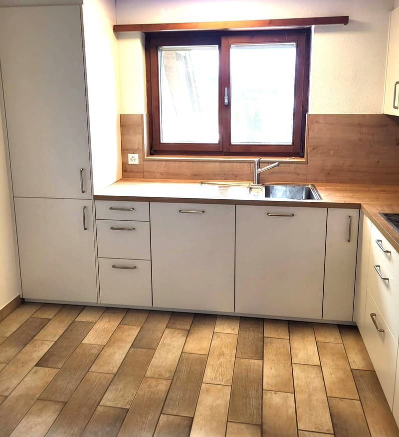 Modern kitchen with white cabinets, wooden countertops, and a stainless steel sink.