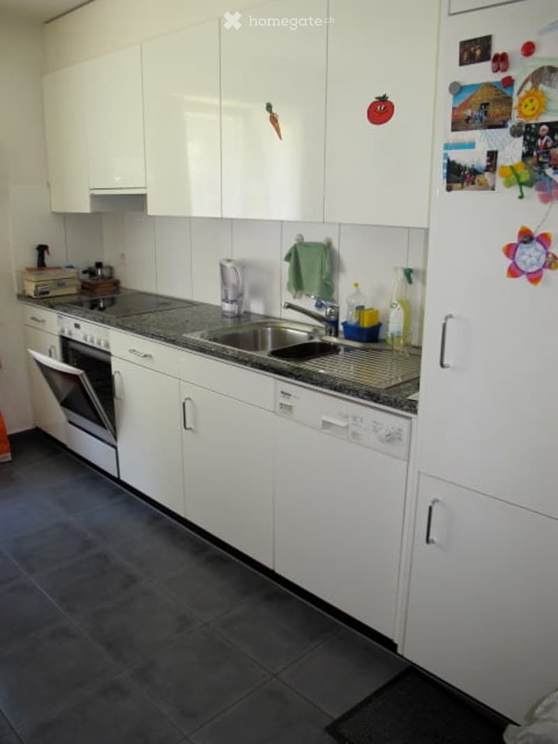 Modern kitchen with white cabinets, stainless steel appliances, and a granite countertop.
