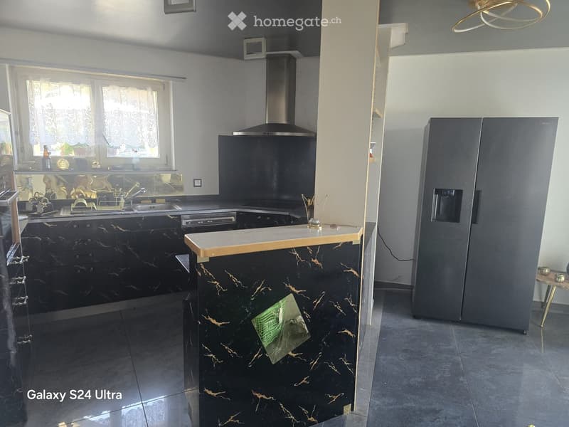 Modern kitchen with black marble cabinets, stainless steel appliances, and a central island with a wooden countertop.