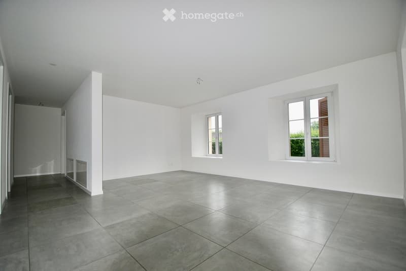 Empty room with white walls, gray tiles, and large windows
