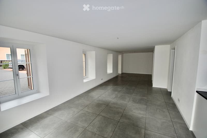 empty room with gray tiled floor, white walls, three windows, electrical outlet on wall