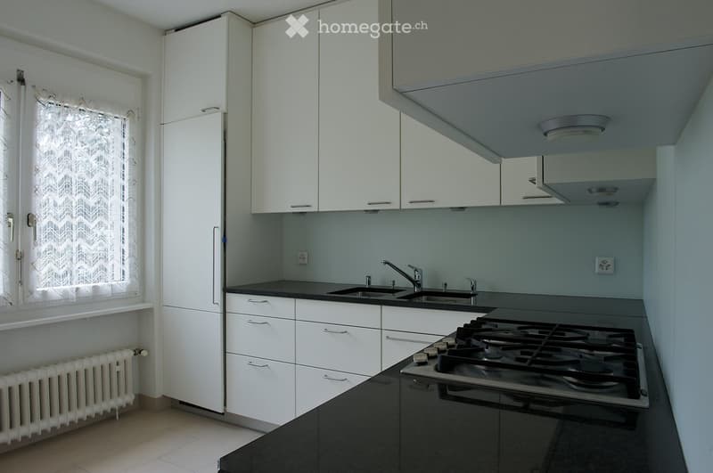 Modern kitchen with white cabinets, black countertops, a double sink, and a gas stove.