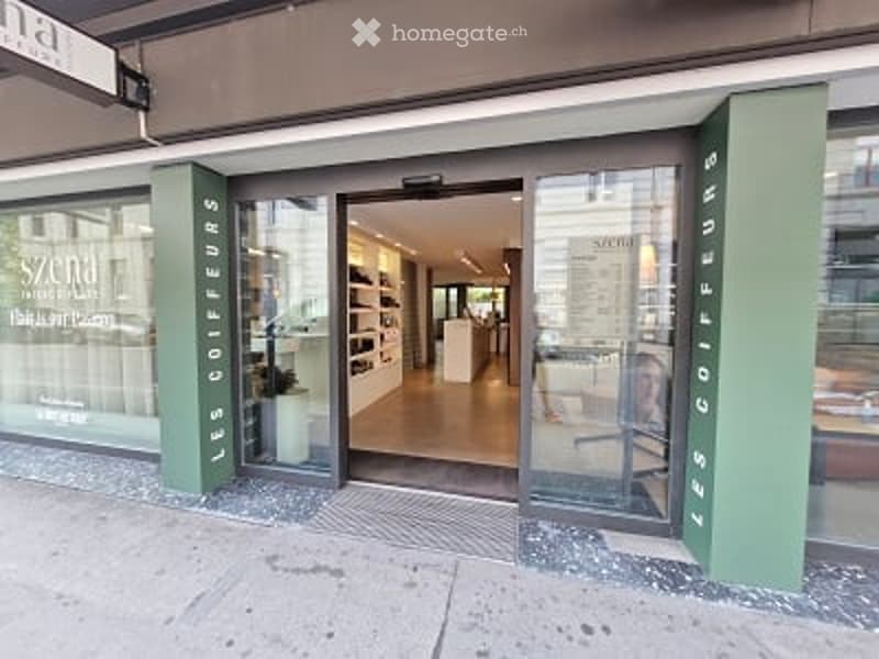 Storefront with glass doors and windows, interior visible with shelves and a chair.
