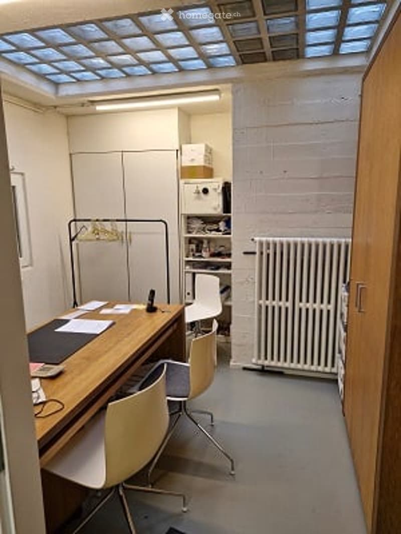 Bright room with a large skylight, wooden desk, chairs, radiator, and shelves.