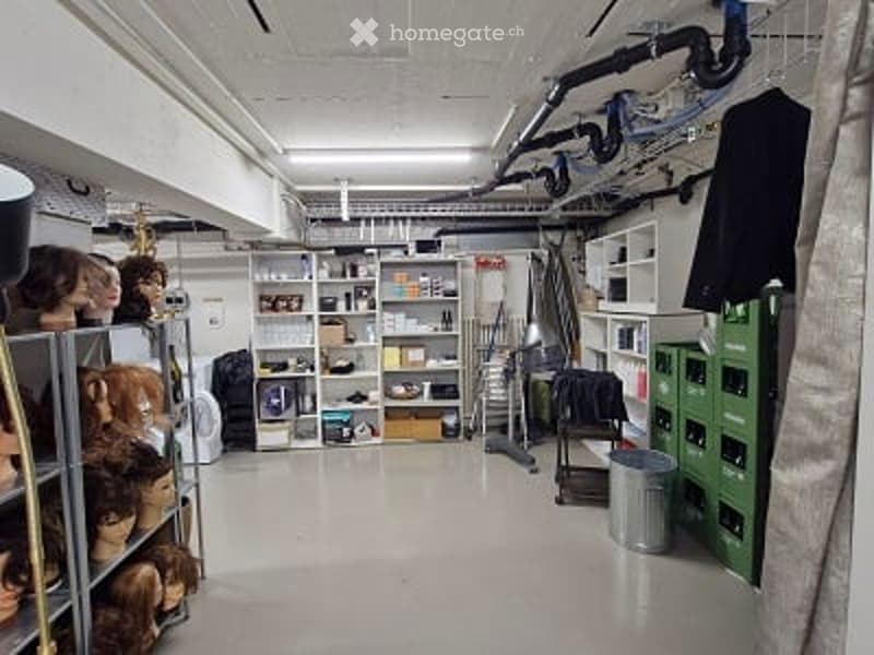 Storage area with shelves, tools, clothing, and various storage bins. Features a stool and a trash can.
