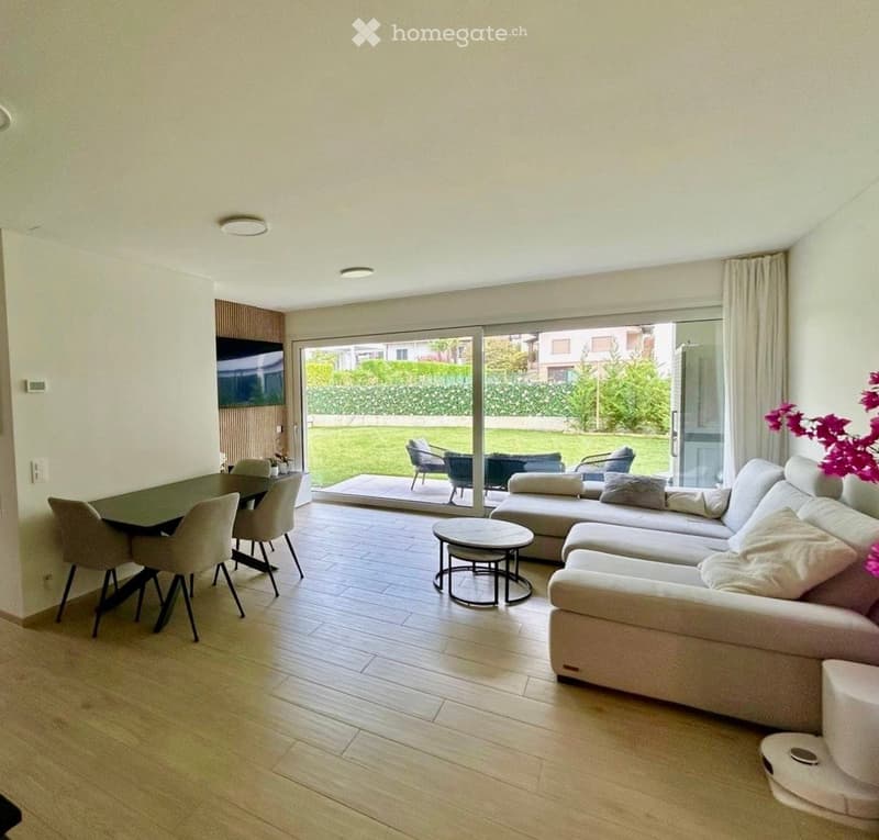 Modern living and dining area with light wood flooring, large glass sliding doors leading to a patio, a sectional sofa, coffee table, dining table with chairs, and a small round table.