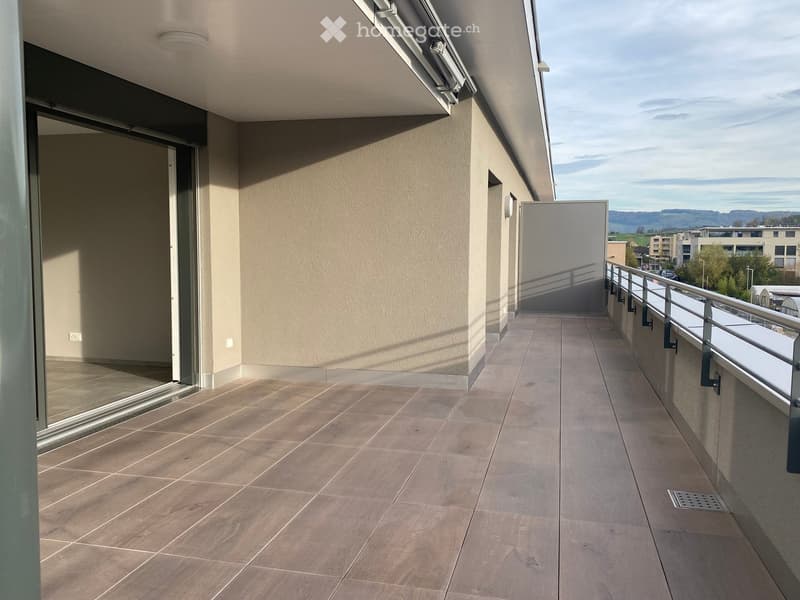 Balcony with tiled floor, metal railing, and a view of the surrounding area.