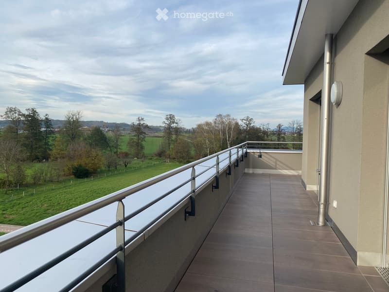 Balcony with modern glass railing, tiled floor, and scenic countryside view.