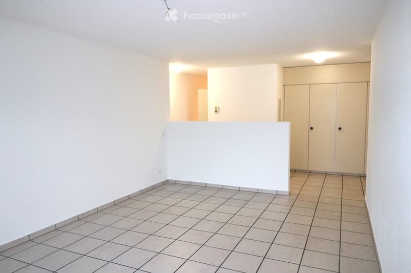 Empty room with tiled floor and white walls, featuring built-in cabinets and a doorway leading to another space.