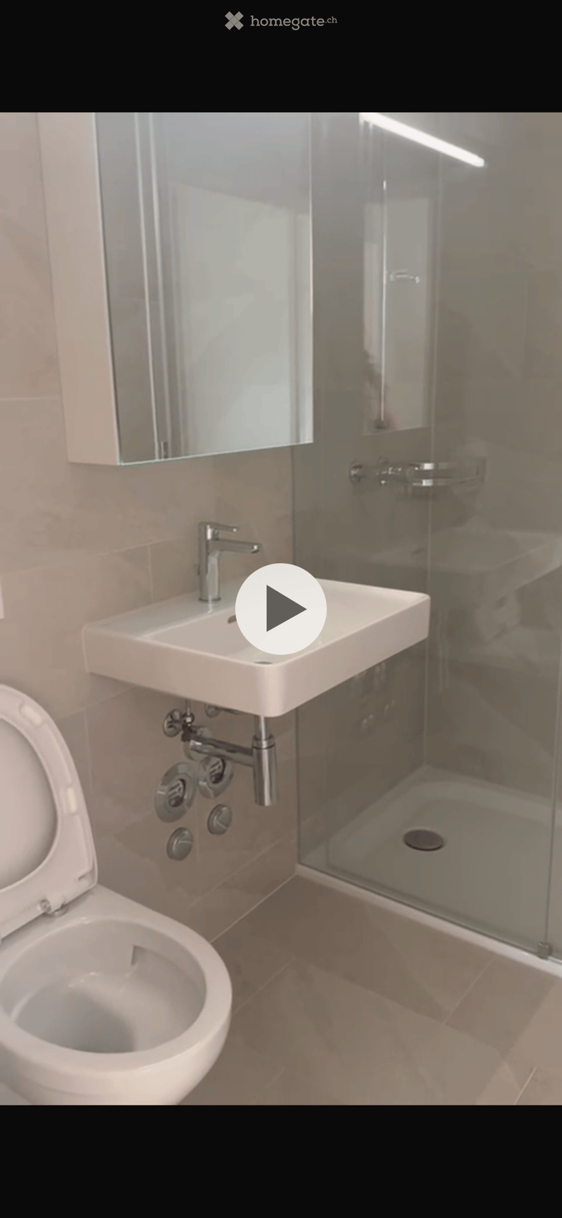 Modern bathroom with a white toilet, a wall-mounted sink with a chrome faucet, and a glass-enclosed shower area.