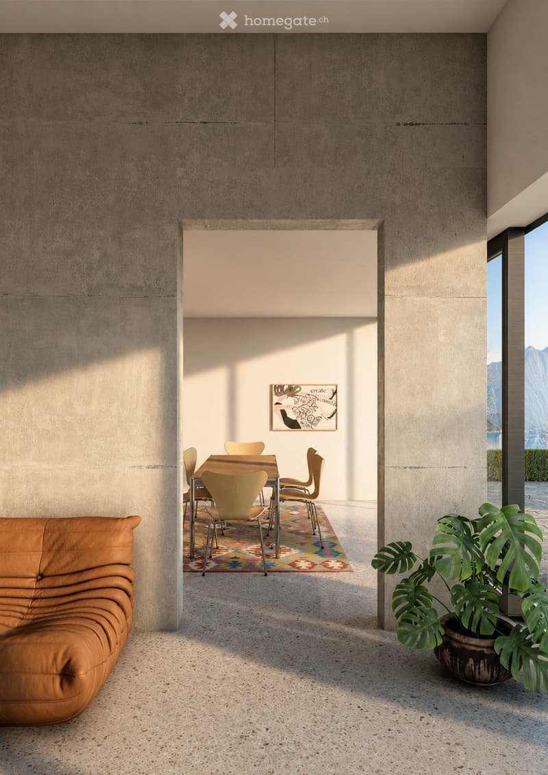 Modern living and dining area with a tan leather sofa, a colorful patterned rug, a dining table with chairs, and a large leafy plant in a pot.