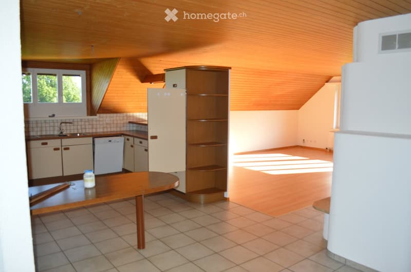 Bright kitchen with wooden ceiling and walls, featuring a refrigerator, dishwasher, sink, and a wooden table with a cup on it.