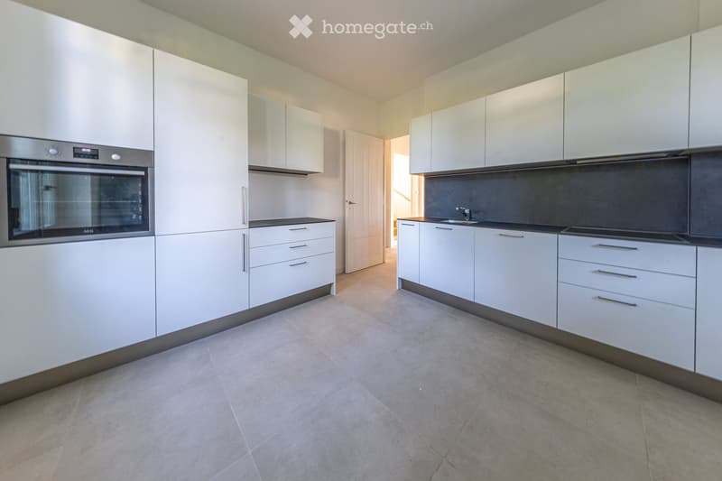Modern kitchen with white cabinets, stainless steel oven, and a sink with a faucet.