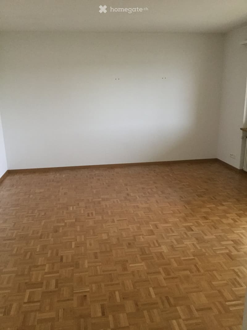 Empty room with wooden herringbone flooring and white walls, no furniture or equipment present.