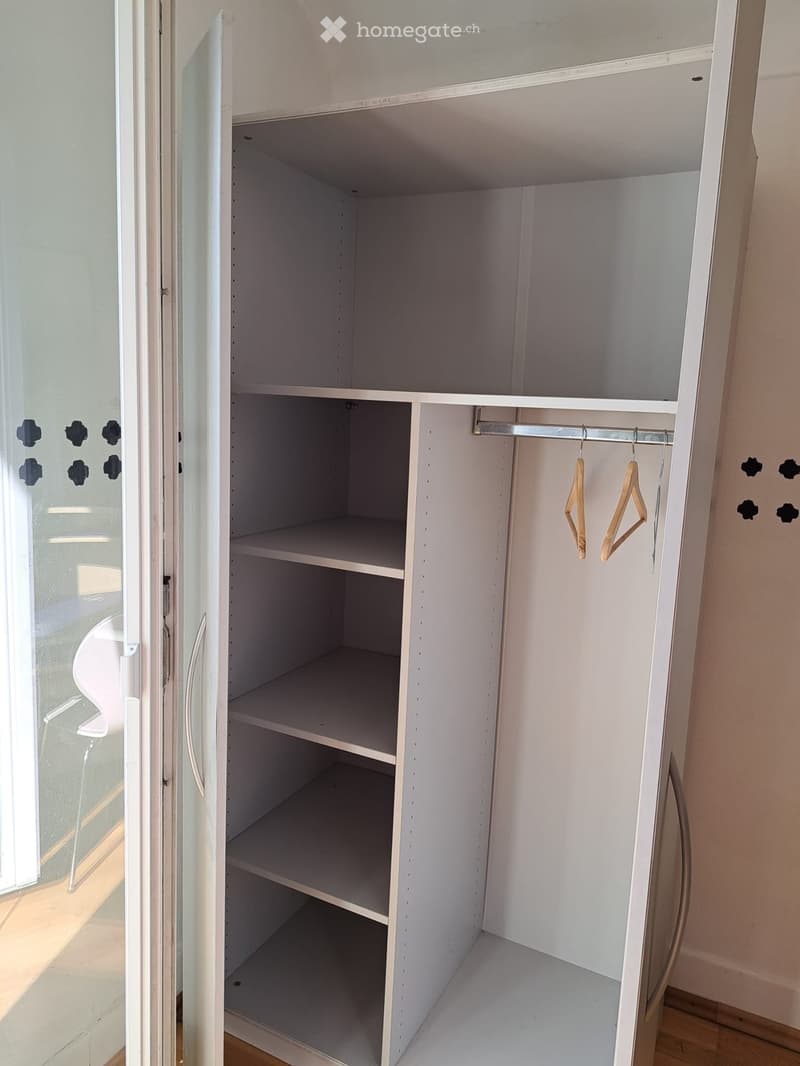 Empty white closet with multiple shelves and a hanging rod, no items inside.
