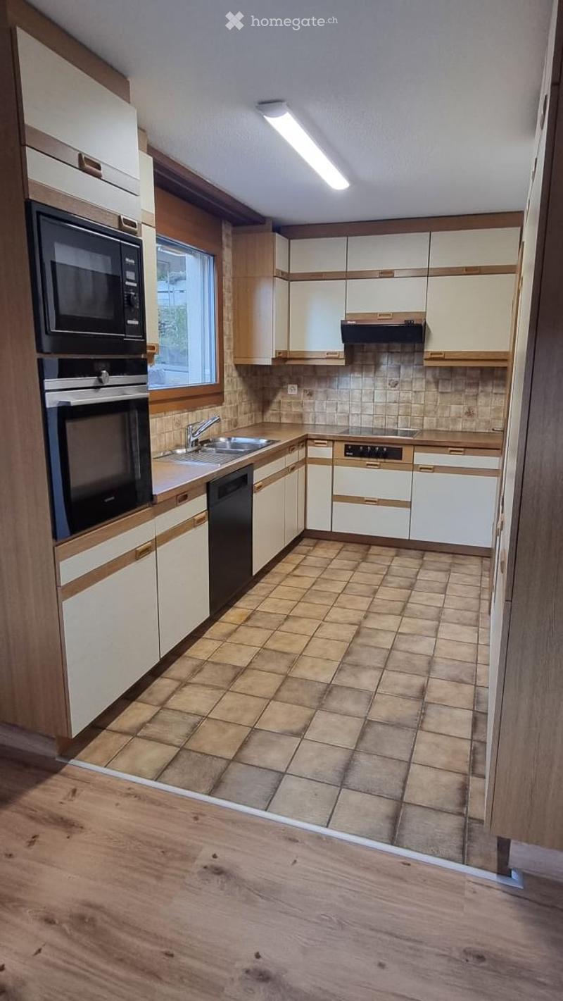 Modern kitchen with white and wood cabinets, stainless steel appliances, tiled floor, and a window above the sink.