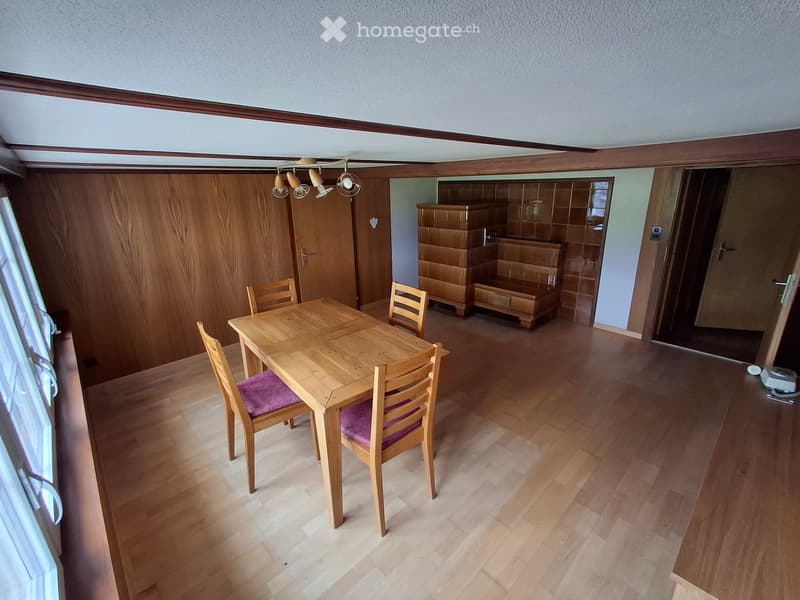 Bright kitchen with wooden flooring, a dining table with four chairs, and built-in wooden cabinets.