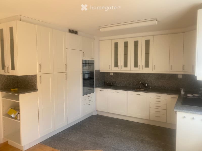 Modern kitchen with white cabinets, dark countertops, and built-in appliances including an oven and sink.