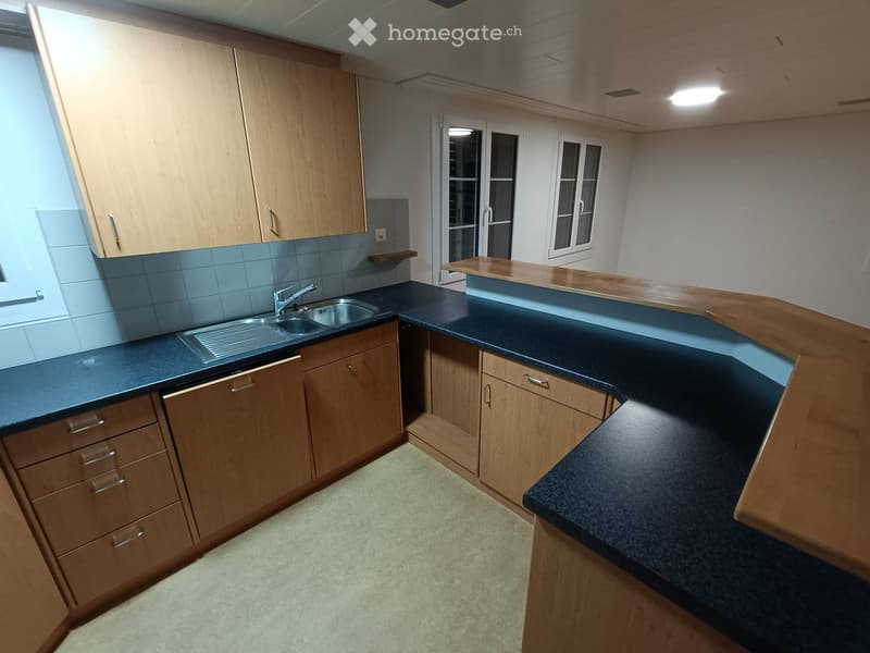 wooden cabinets, black counter top, white tiled wall, stainless steel sink, dishwasher, power outlet