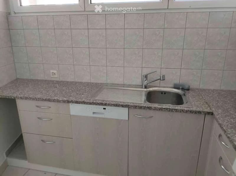 Modern kitchen with granite countertop, stainless steel sink, and light-colored cabinets.