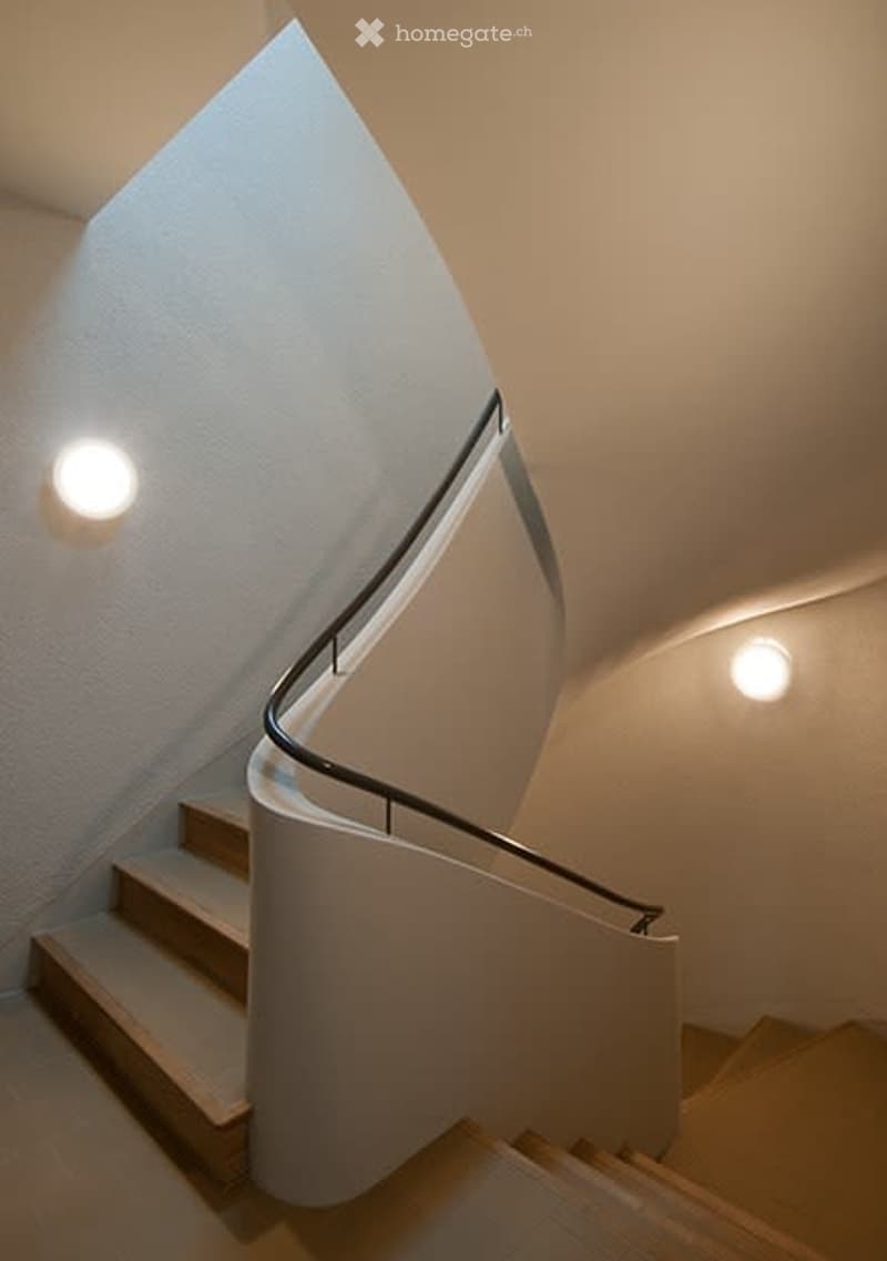 curved wooden stairs, white walls, ceiling lights