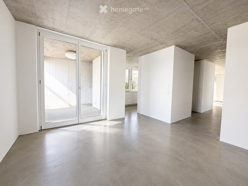 Empty room with white walls, polished concrete floor, and large sliding glass doors leading to another space.