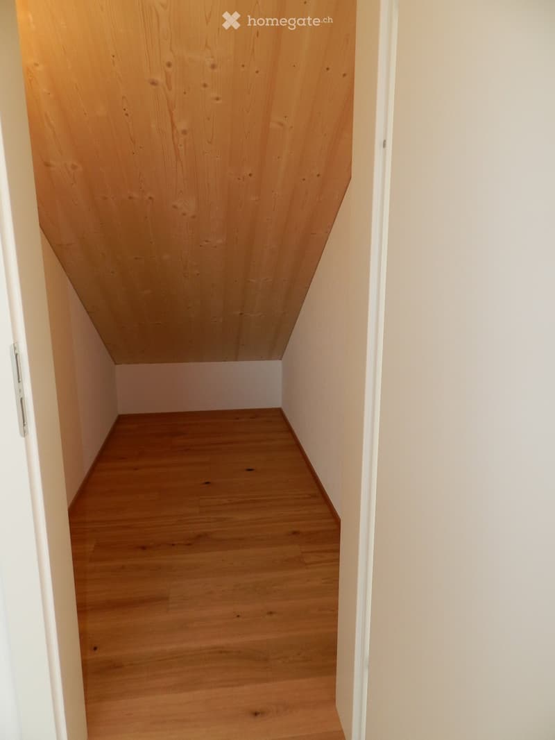 Empty wooden staircase with light-colored wooden steps and white walls.